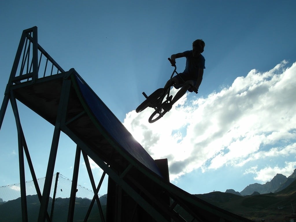 Mountain biker performing a jump by biking on a ramp symbolizing extreme sports